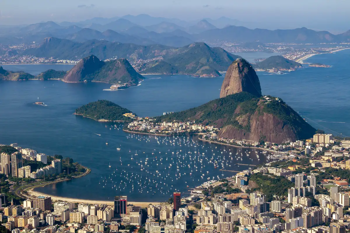 Vista aérea do Pão de Açúcar e da Baía de Guanabara, no Rio de Janeiro, com barcos ancorados e prédios da orla