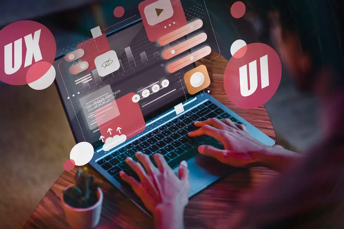 Mãos digitando em um notebook, com ícones de interface e layout flutuando sobre a tela