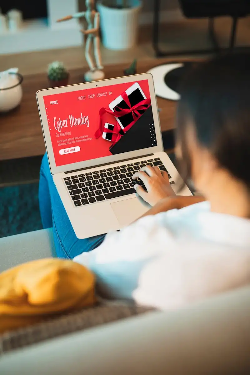 Pessoa sentada no sofá com um notebook aberto em uma página de promoção de Cyber Monday